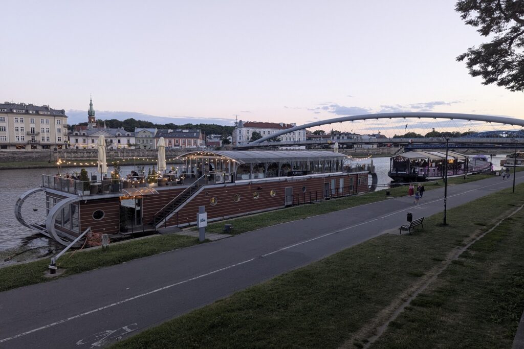 Vista sulla Vistola a Cracovia al tramonto con barca ristorante illuminata