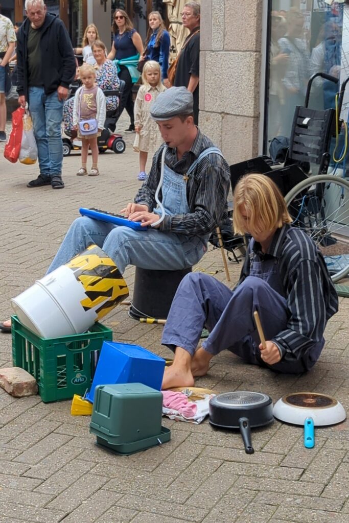 Danimarca on the Road: il viaggio che non ti aspetti 25 Due musicisti di strada si esibiscono nel centro storico di Odense, contribuendo all'atmosfera vivace della città durante il periodo estivo.