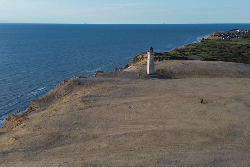 Danimarca on the Road: il viaggio che non ti aspetti 13 Il faro di Rubjerg Knude fotografato dal drone al tramonto, circondato dall'immensa duna di sabbia e affacciato sulla costa occidentale della Danimarca.