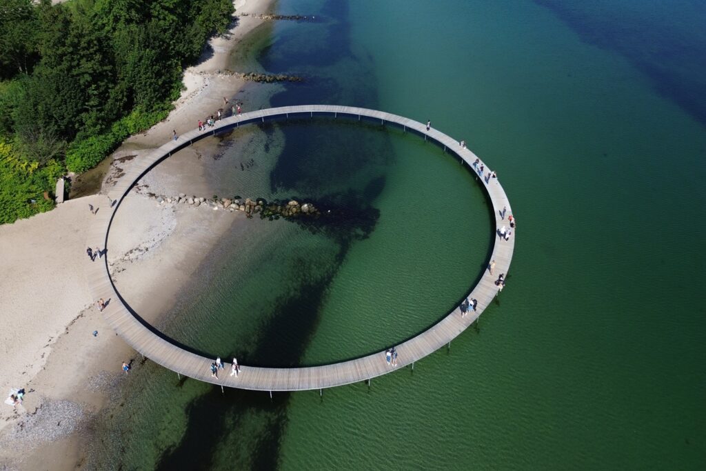 Danimarca on the Road: il viaggio che non ti aspetti 17 Veduta aerea dell'Infinite Bridge di Aarhus, il caratteristico ponte circolare in legno che si estende sul mare lungo la costa danese.