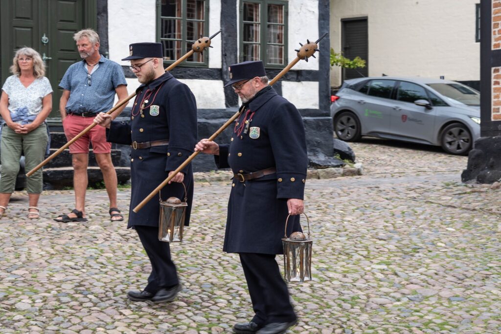 Danimarca on the Road: il viaggio che non ti aspetti 20 Due Vaegterne percorrono le vie del centro storico di Ebeltoft con lanterne e uniforme tradizionale durante la ronda serale.