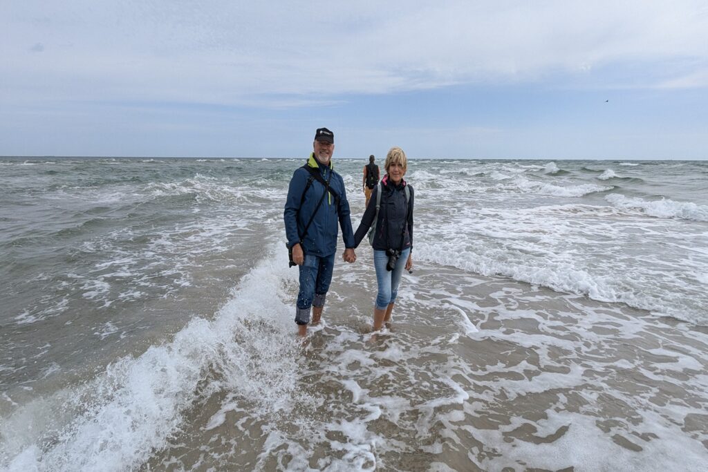 Danimarca on the Road: il viaggio che non ti aspetti 7 Due viaggiatori camminano nell'acqua a Grenen, nel punto in cui il Mare del Nord incontra il Mar Baltico, all'estremità settentrionale della Danimarca.