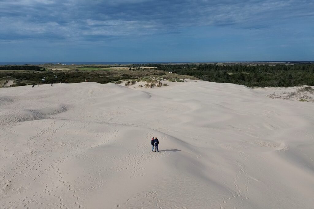 Danimarca on the Road: il viaggio che non ti aspetti 15 Veduta aerea di Råbjerg Mile, la più grande duna mobile della Danimarca, con due persone al centro della distesa di sabbia e il paesaggio naturale circostante.