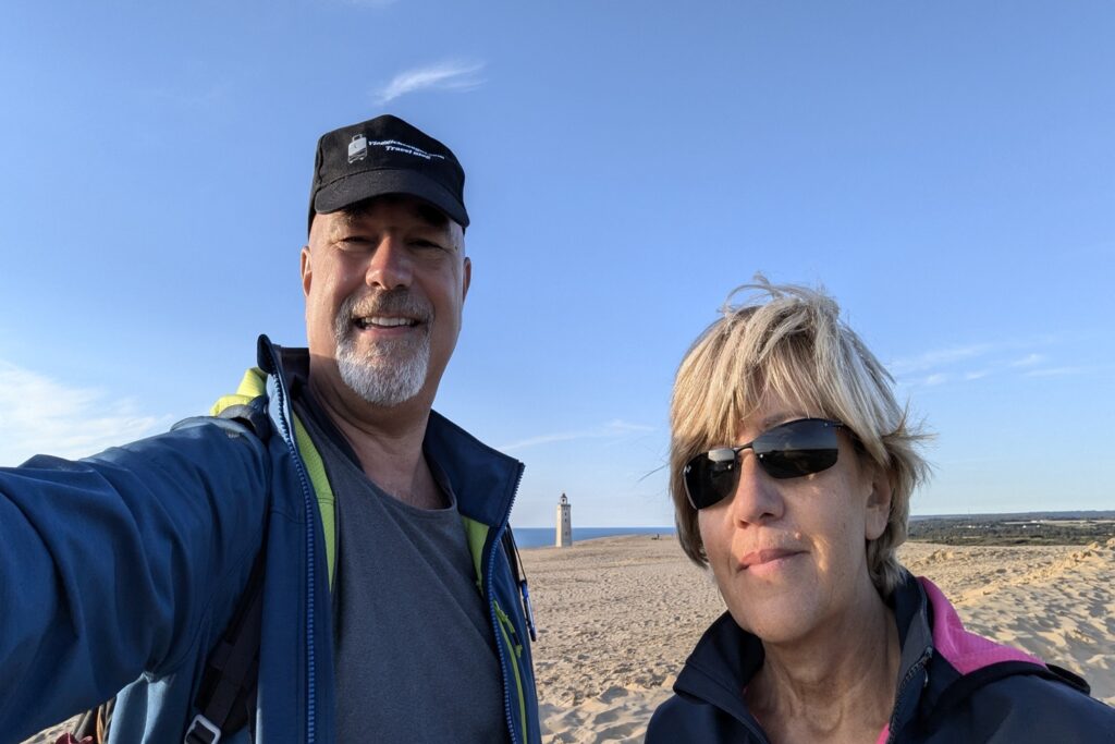 Danimarca on the Road: il viaggio che non ti aspetti 12 Alberto e Patrizia sulla duna di Rubjerg Knude con il faro sullo sfondo al tramonto, lungo la costa occidentale della Danimarca.