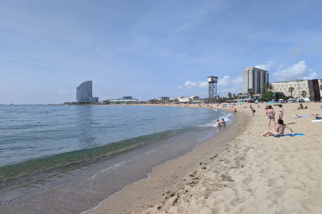 Barcellona in 6 giorni: molto più della città di Gaudí 23 Panorama della spiaggia della Barceloneta con il mare, l'Hotel W e la Torre del Teleférico sullo sfondo a Barcellona.